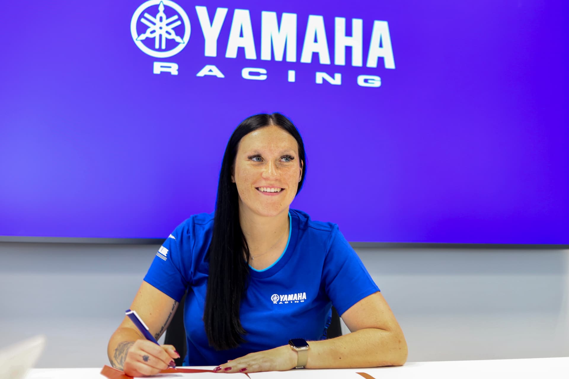 Amandine Verstappen signant son contrat d'Ambassadrice Officielle Yamaha, devant le logo Yamaha Racing